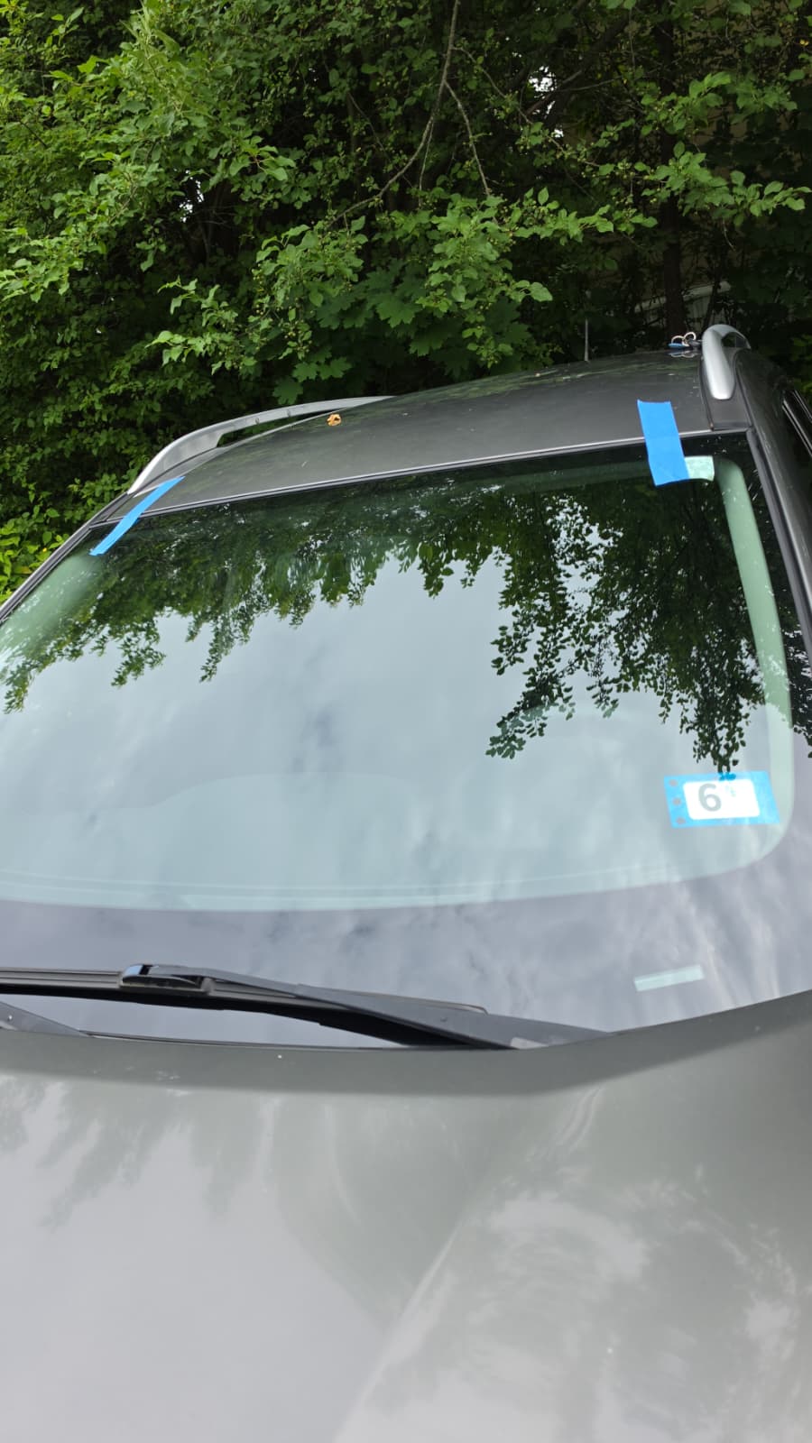 Freshly installed windshield secured with blue tape